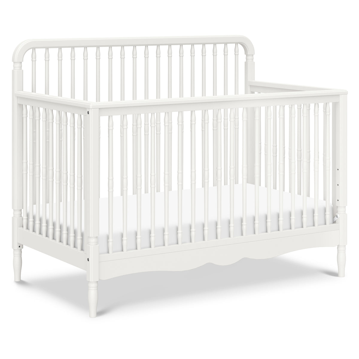 Three-quarter view of Liberty 4-in-1 convertible spindle crib in warm white showcasing thick turned spindles and scalloped base on white background