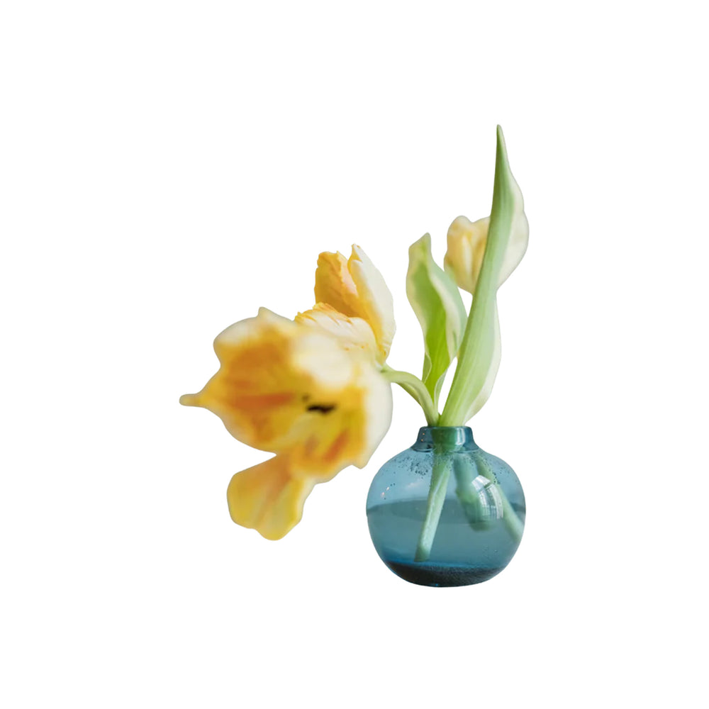 Front view of small round blue glass bud vase showcasing bubbled recycled-glass texture on white background