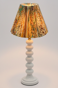 Lit hand-marbled pleated empire lampshade on white stacked base