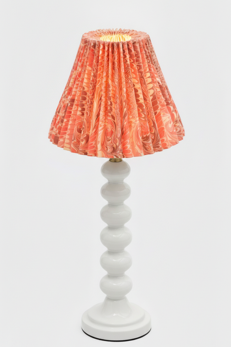 Table lamp with white stacked base and lit hand-marbled pleated lampshade