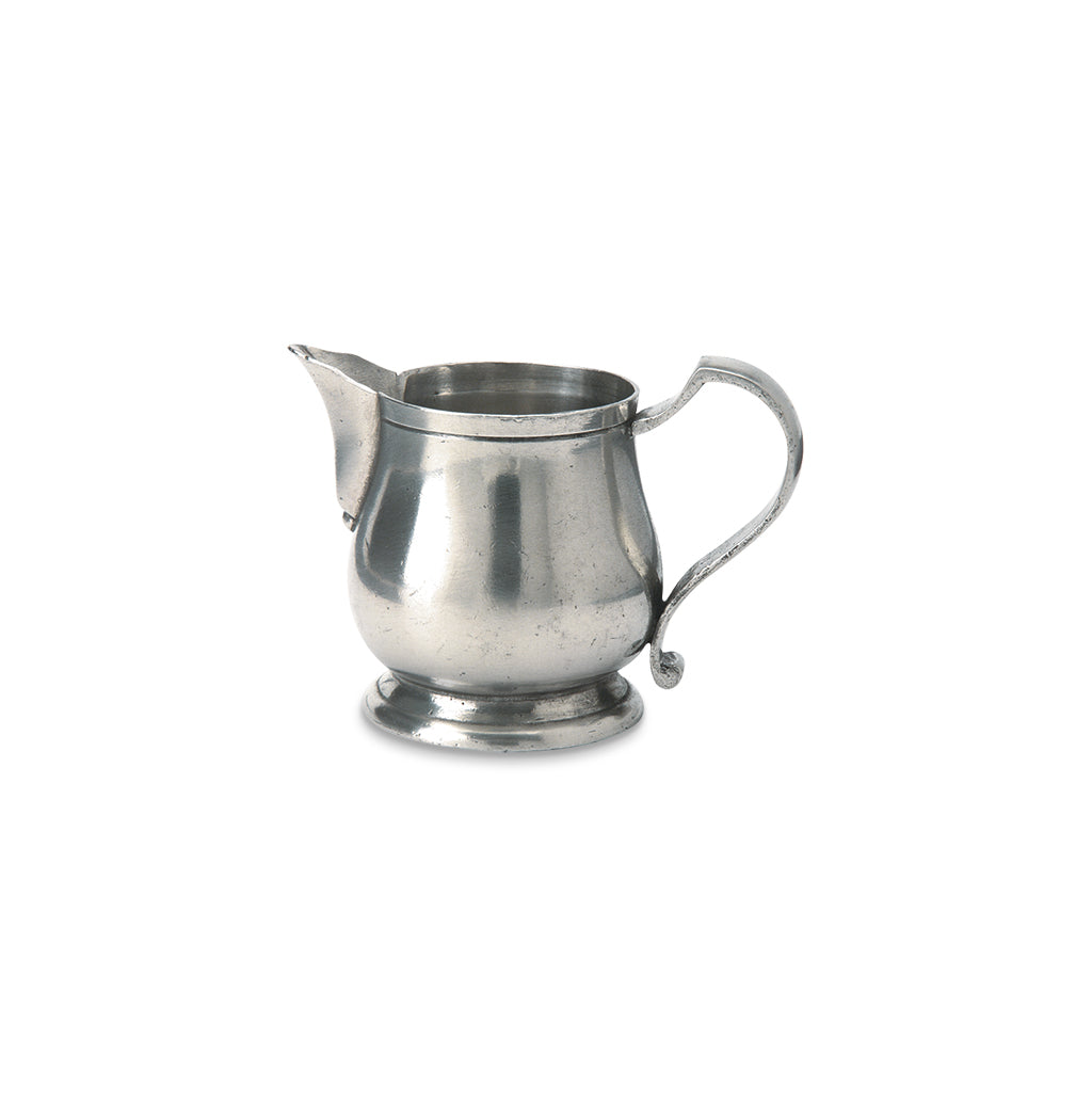 Front view of pewter creamer showcasing its spout and curved handle with a white background