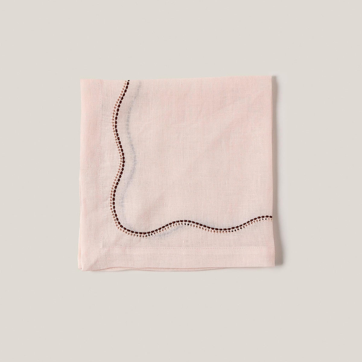 Front view of Le Chemin Napkin in Light Pink showcasing curved ajouré and appliqué detailing on linen against a neutral background