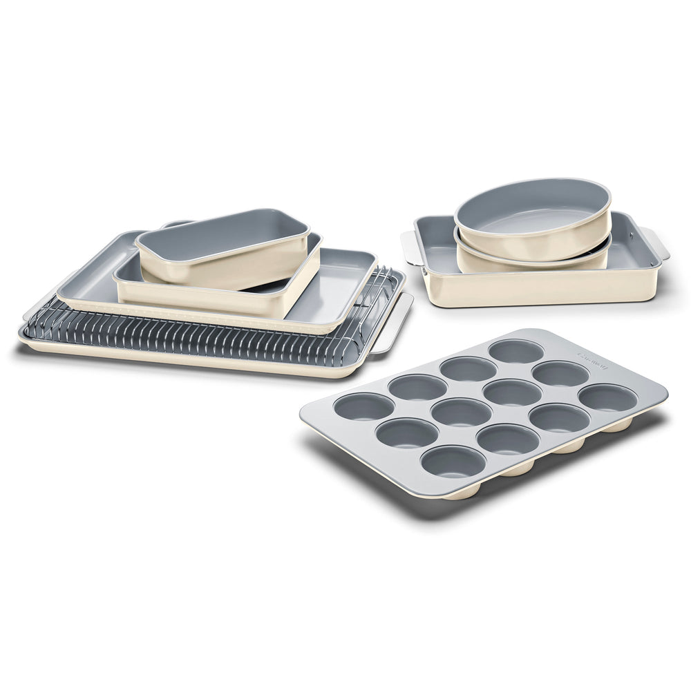 Angled view of 11-piece bakeware set in cream with gray nonstick interior, includes pans, muffin tray, and cooling rack