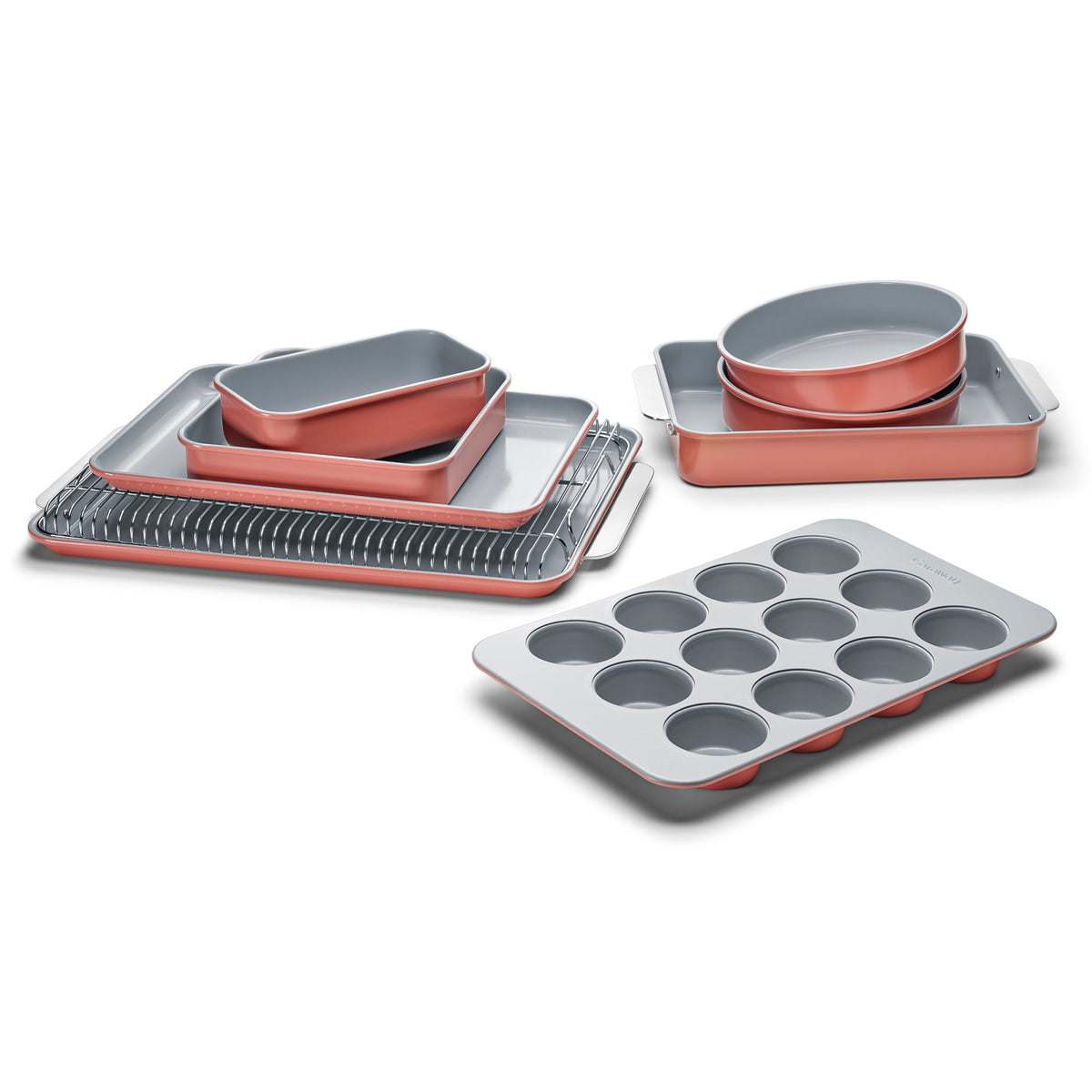 Angled view of 11-piece bakeware set in coral with gray nonstick interiors, showing muffin, round, and rectangular pans