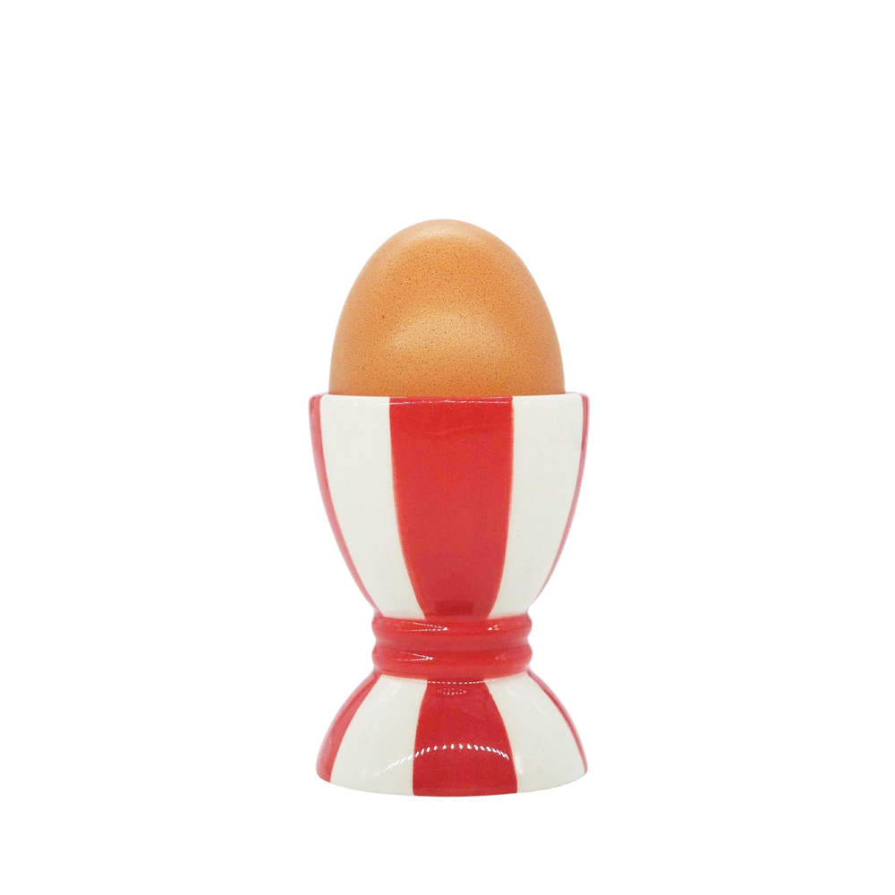 Front view of the red and white striped ceramic egg cup holding an egg against a black background
