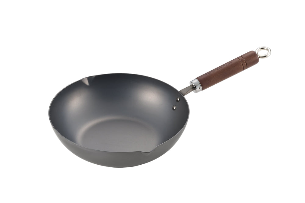 Angled view of Classic Black carbon steel deep fry pan with deep sides, pour spouts, and wooden handle on white background