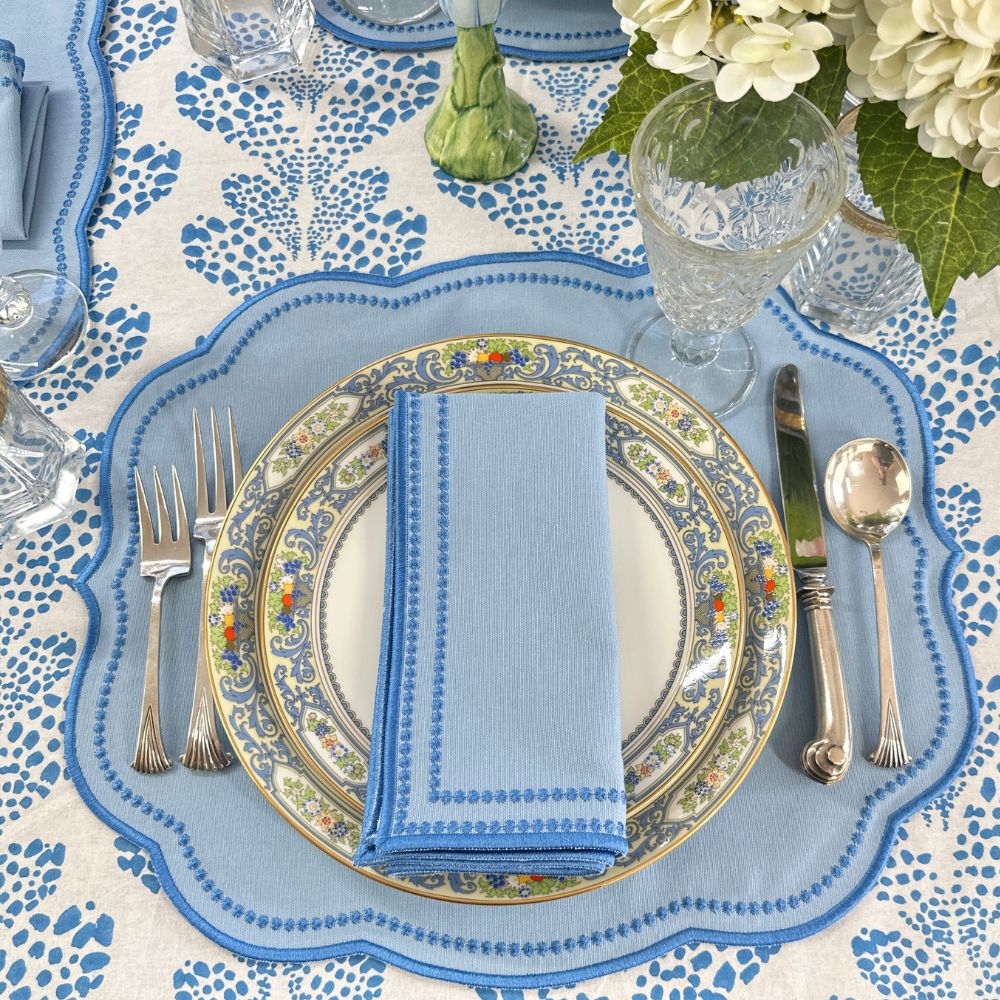 Elegant table setting with floral centerpiece, blue and white tablecloth, and silverware.