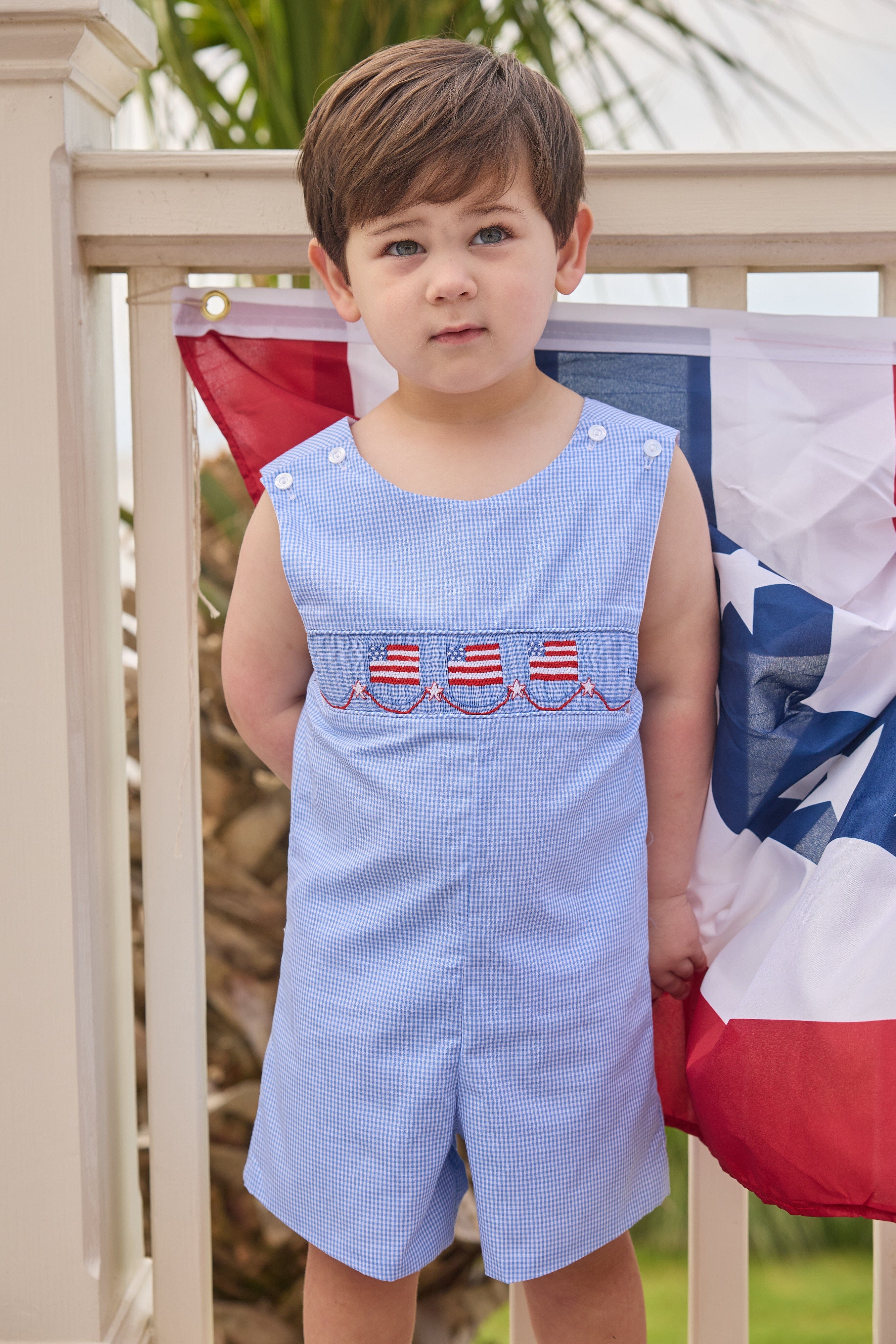 Little English traditional children's clothing.  Classic john john for toddler boys in royal blue mini gingham with American flag smocking at the chest