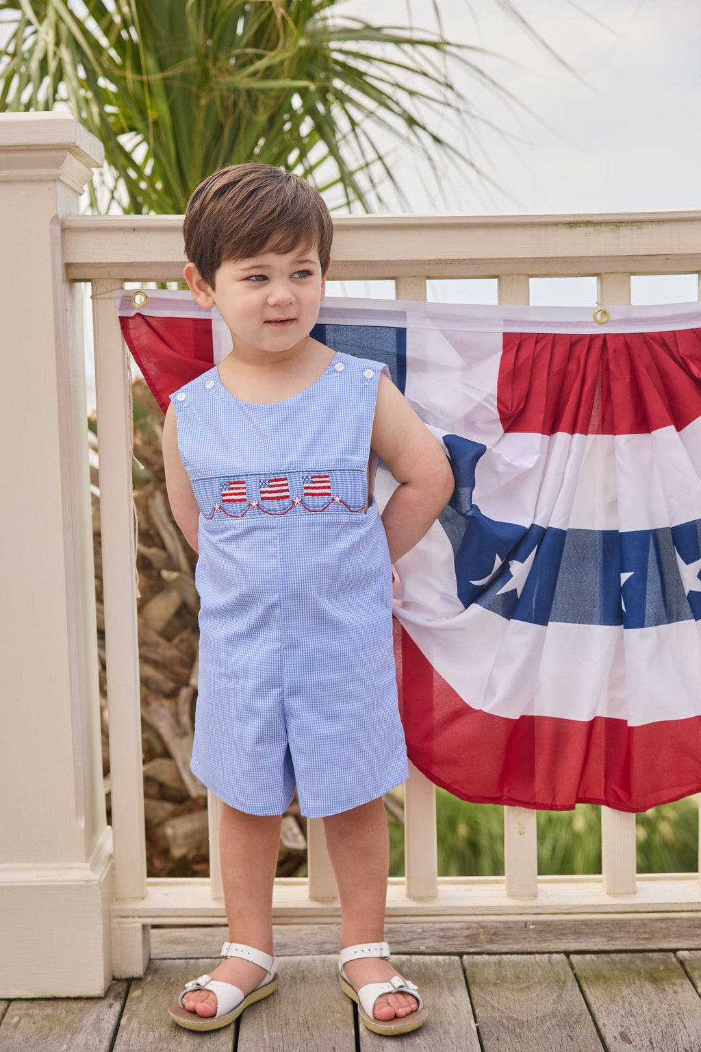 Little English traditional children's clothing.  Classic john john for toddler boys in royal blue mini gingham with American flag smocking at the chest