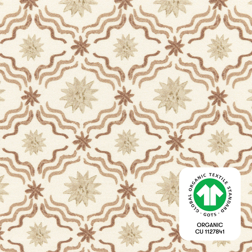 Close-up of All Stages Bassinet Sheet in Autumn Star showing starburst and wavy pattern with GOTS organic textile badge