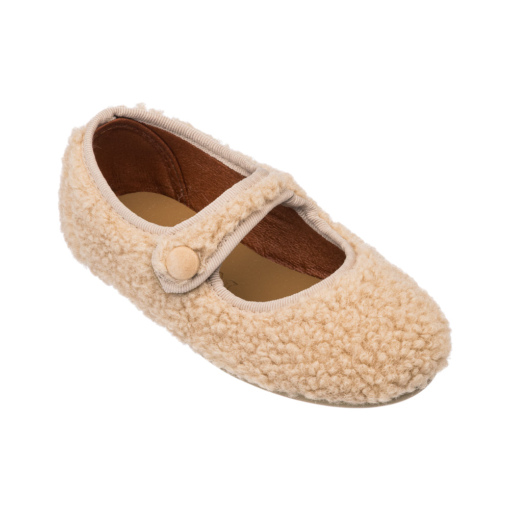 Three-quarter top view of shearling Mary Jane slipper showcasing beige curly shearling exterior, button strap, and brown lined interior on white background