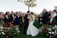 Bride and groom kiss during their Pebble Beach wedding ceremony surrounded by guests and flowers