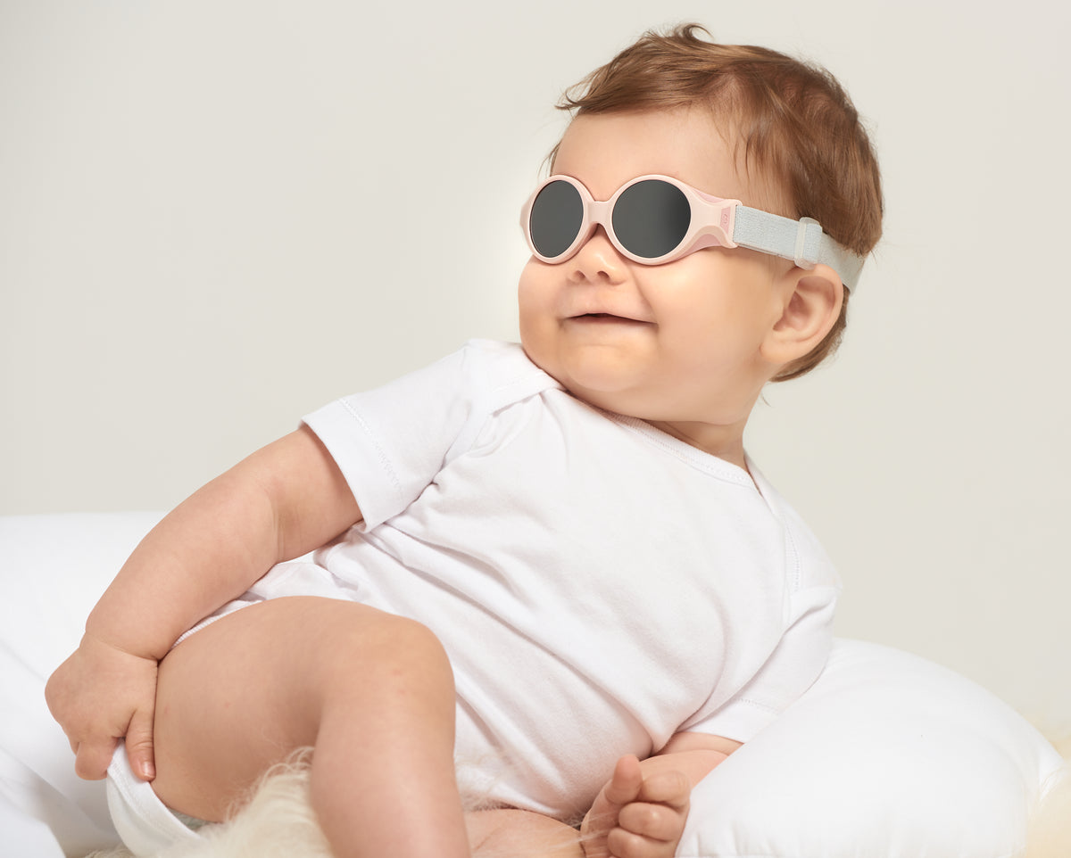Close-up view of Glee Infant Sunglasses in Chalk Pink showcasing the elasticated headband on a baby against a light background