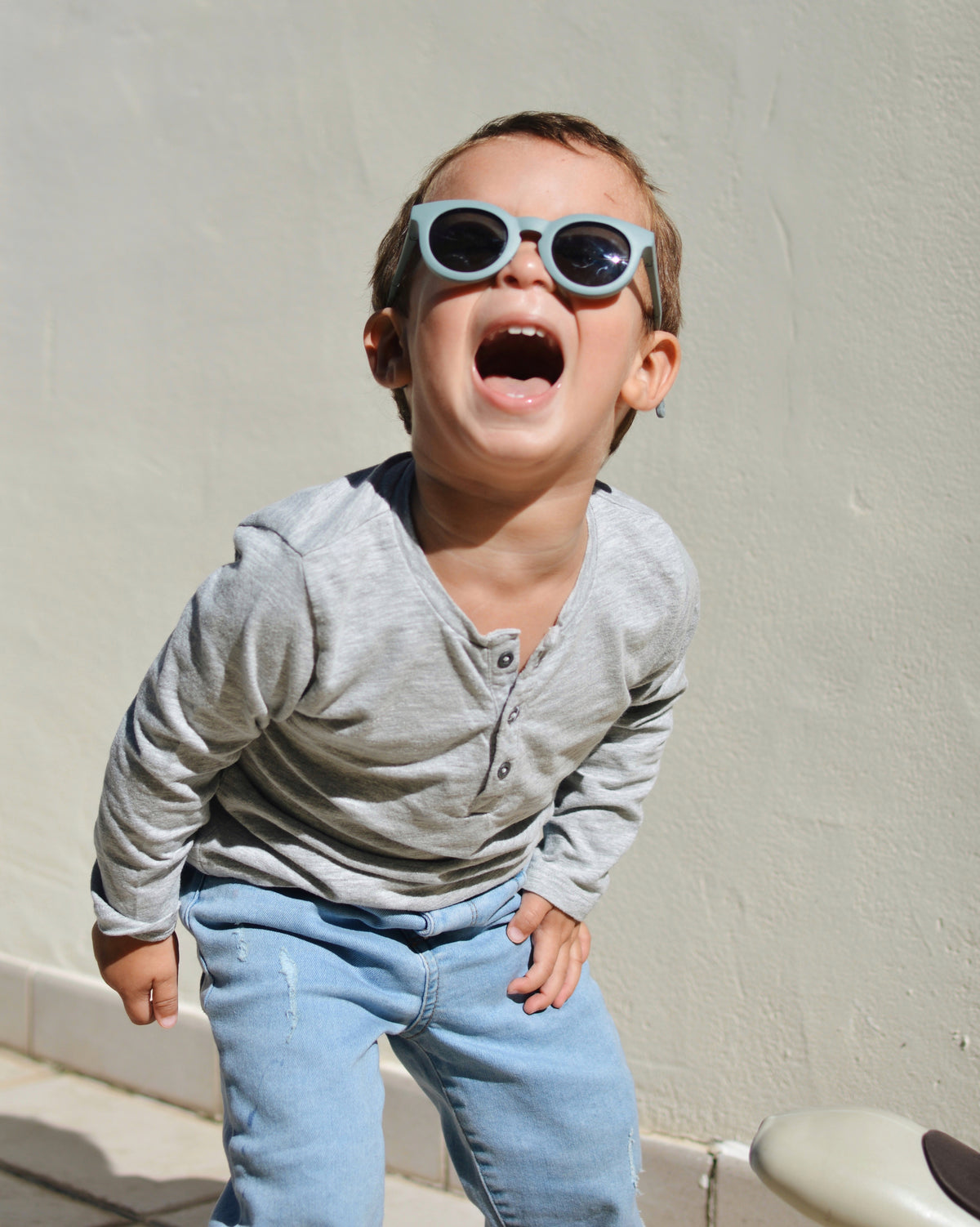 Child wearing Baltic Blue Happy Infant Sunglasses and smiling indoors