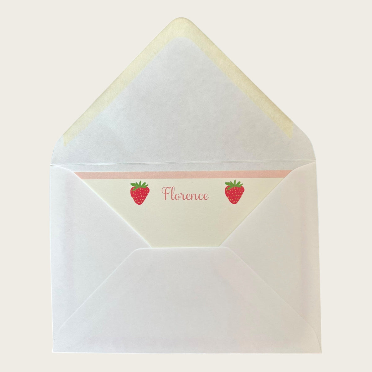 Open envelope view of Strawberry notecard showcasing cream liner printed with two red strawberries and personalized name Florence on light background