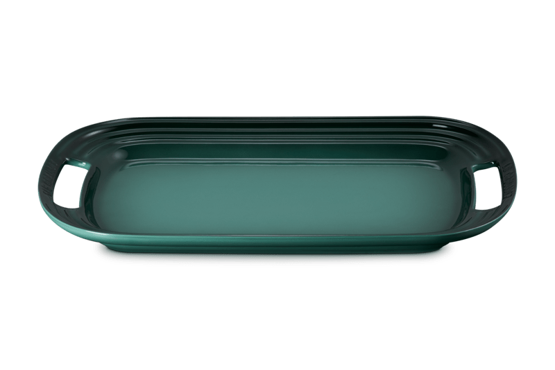 Front view of Le Creuset 16.25-inch serving platter in Artichaut with integrated handles and ridged edges on white background