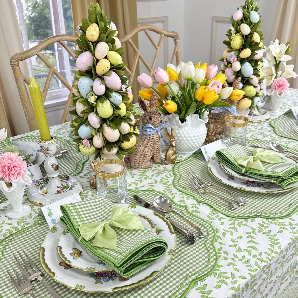Easter-themed table setting with decorative trees, flowers, and bunny figurines.