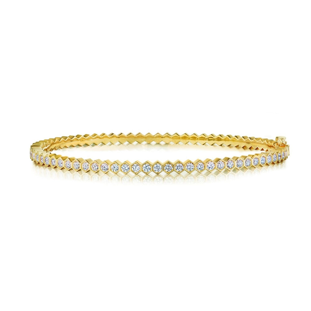 The Hexagon Bezel Set Diamond Bangle showcases a single row of round white diamonds in 18k gold, featuring a secure clasp and reflective underside for extra brilliance.