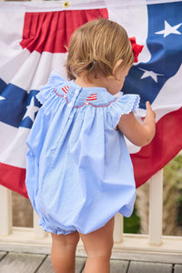 Little English traditional children's clothing.  Flutter sleeve bubble in royal blue mini check fabric and smocking with American flag bunting for baby girls
