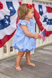 Little English traditional children's clothing.  Flutter sleeve bubble in royal blue mini check fabric and smocking with American flag bunting for baby girls