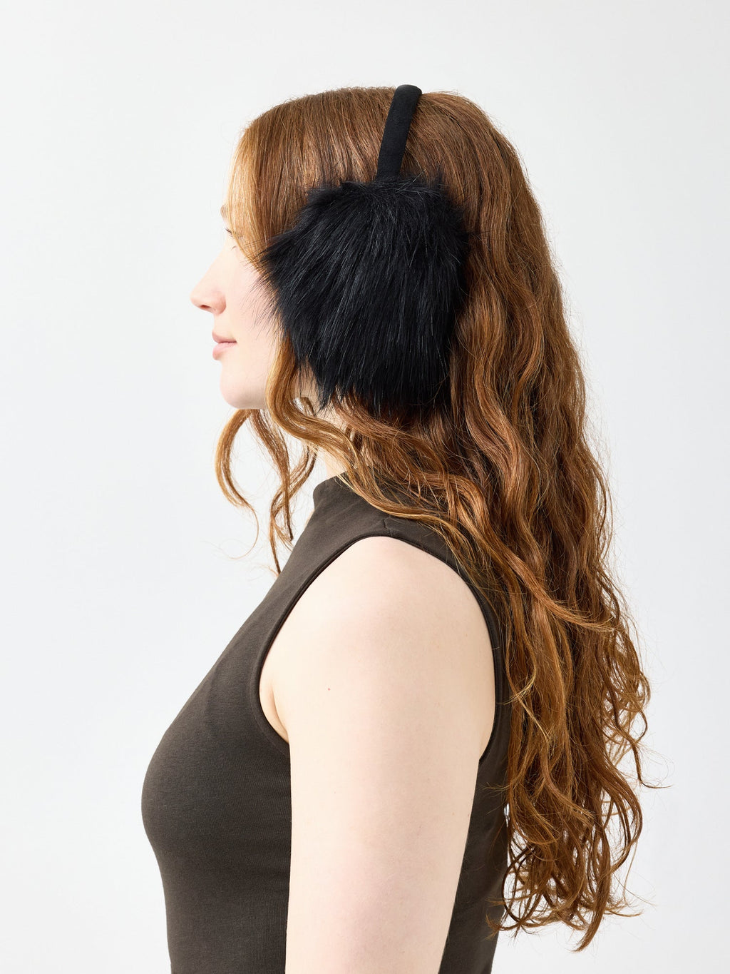 Woman side profile wearing black faux fur ear muffs against a white background