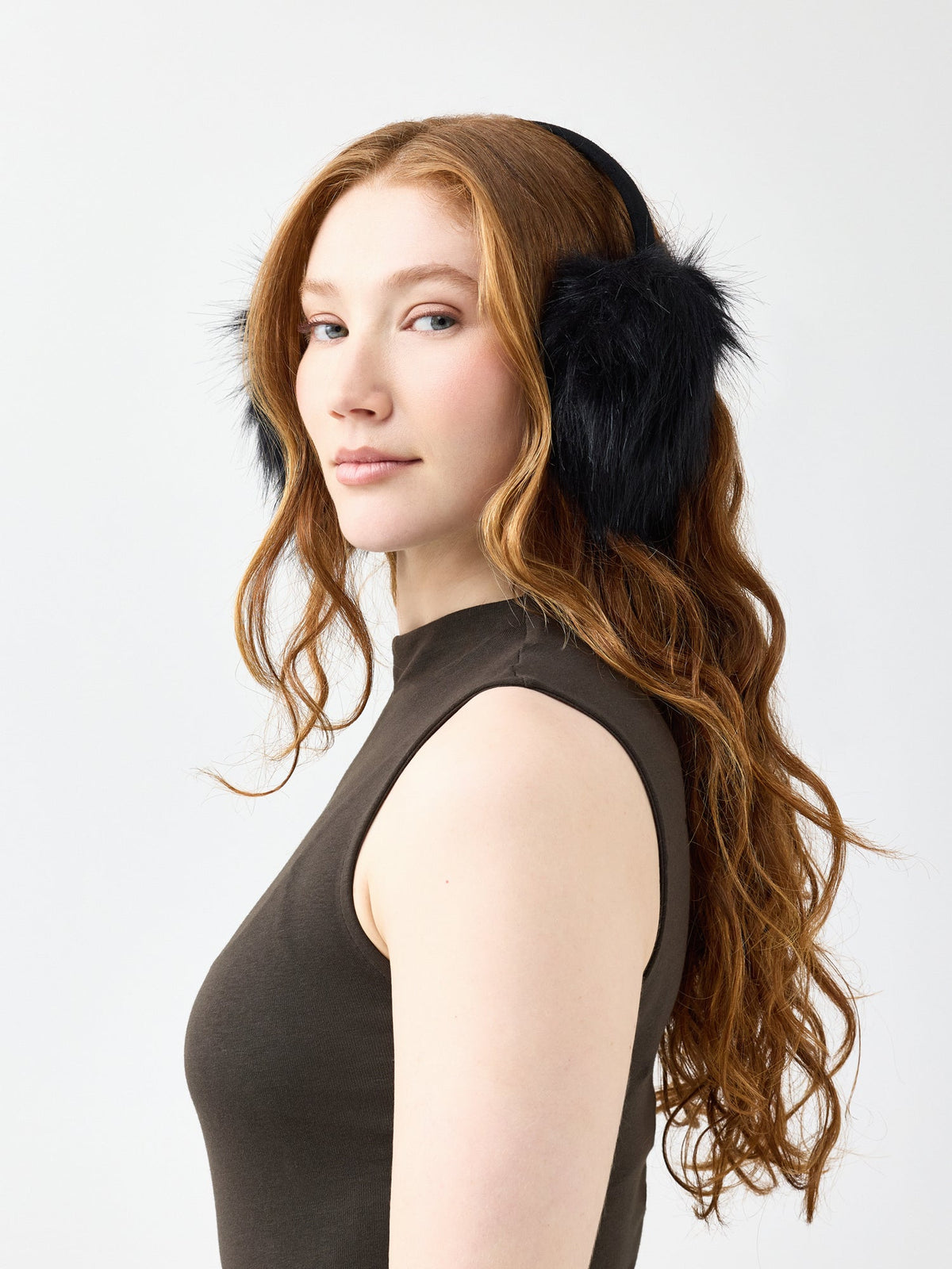 Woman wearing black faux fur ear muffs against a white background