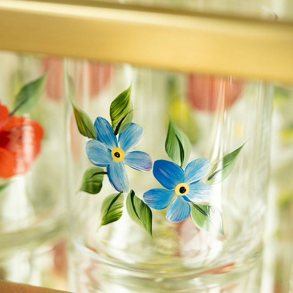 Close-up of Forget Me Not crystal tumbler showing hand-painted blue forget-me-not flowers on clear glass with soft blurred background