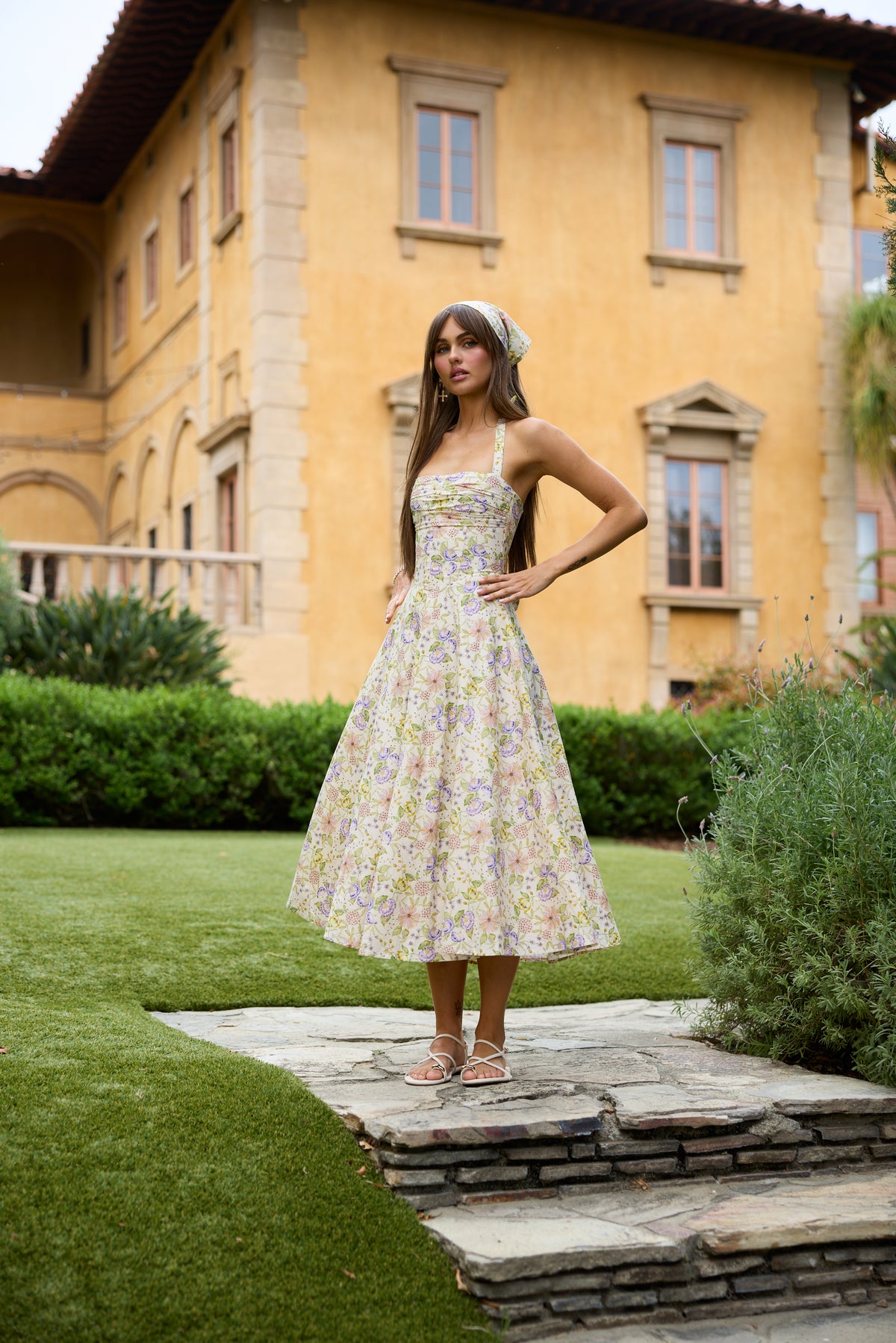Front view of The Amora Dress in Cordoba Print showcasing floral print and midi fit with garden background