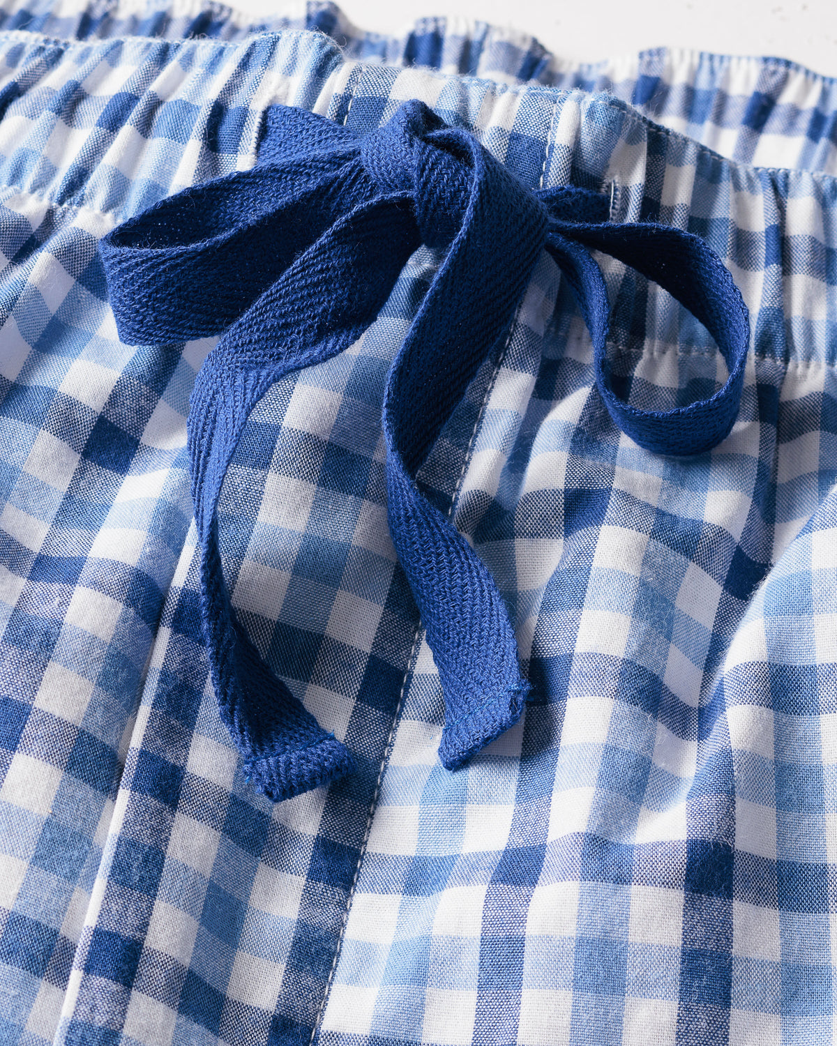 Close-up of the mens twill pajama short set in royal blue gingham by Petite Plume, showcasing a stylish checkered pattern with an elastic waistband, tied with a blue fabric bow.