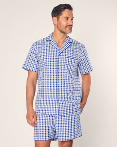 A bearded man with short hair, clad in a Mens Twill Pajama Short Set by Petite Plume in Royal Blue Gingham, gazes to the side, exuding comfort against a plain light gray background.