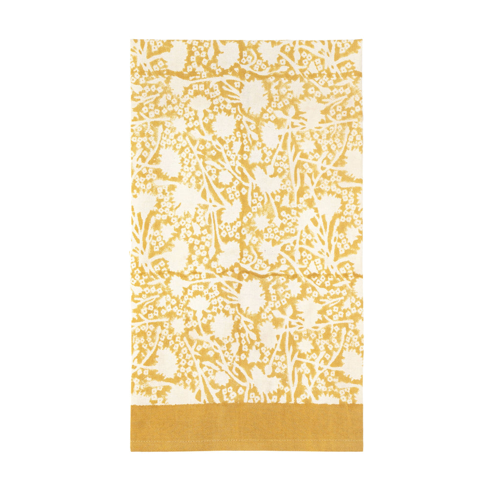 Flat lay of Meadows tea towel in Dijon showing yellow meadow floral pattern and solid mustard hem on white background