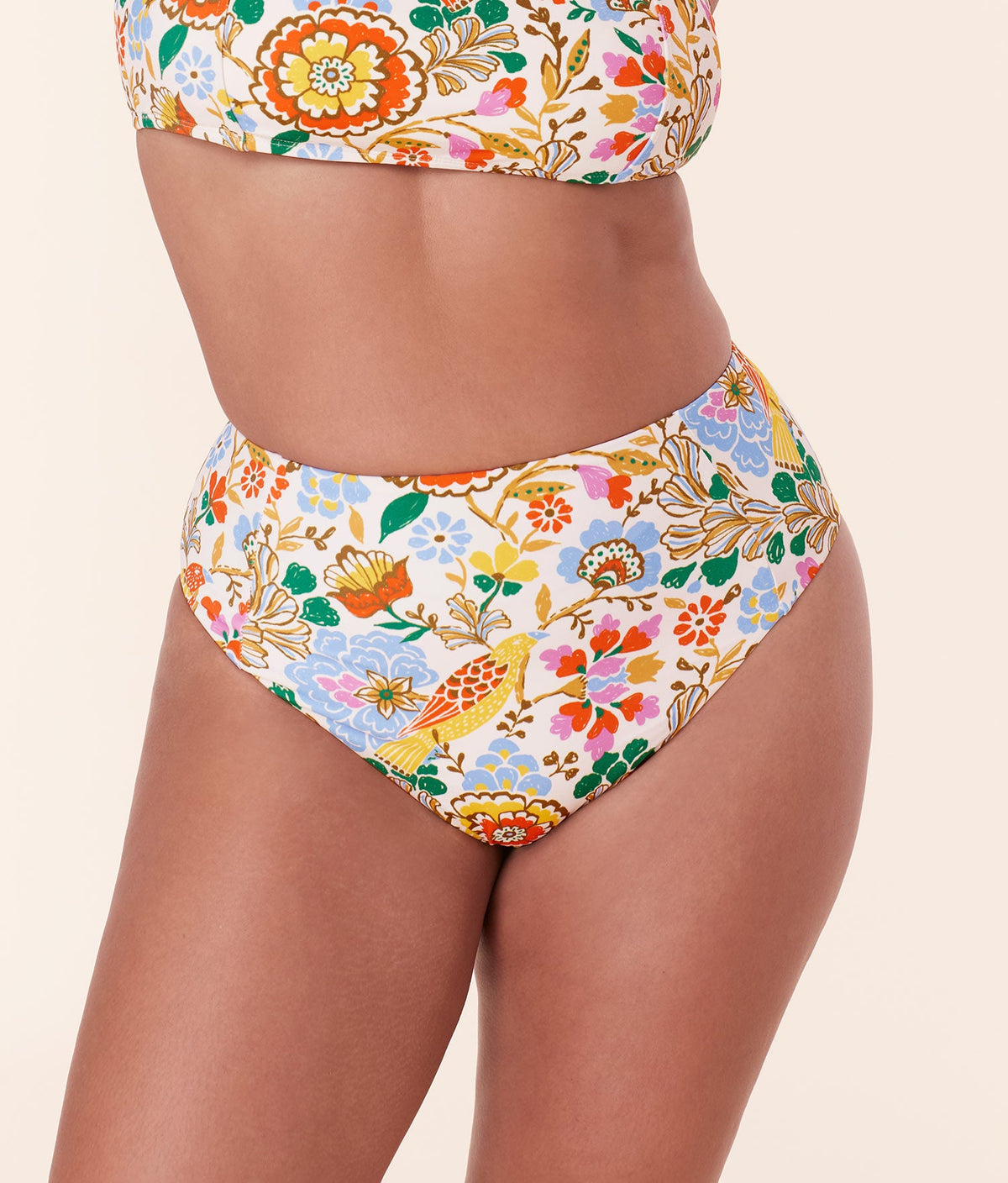 Model wearing Andie Swim Bird Floral High Waist Cheeky Bikini Bottom with vibrant floral and bird design, high-rise fit.