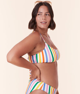 Model wearing Andie Swim's Fiji Bikini Top in Rainbow Stripe, featuring a scoop neckline and adjustable criss-cross straps for a secure, custom fit.