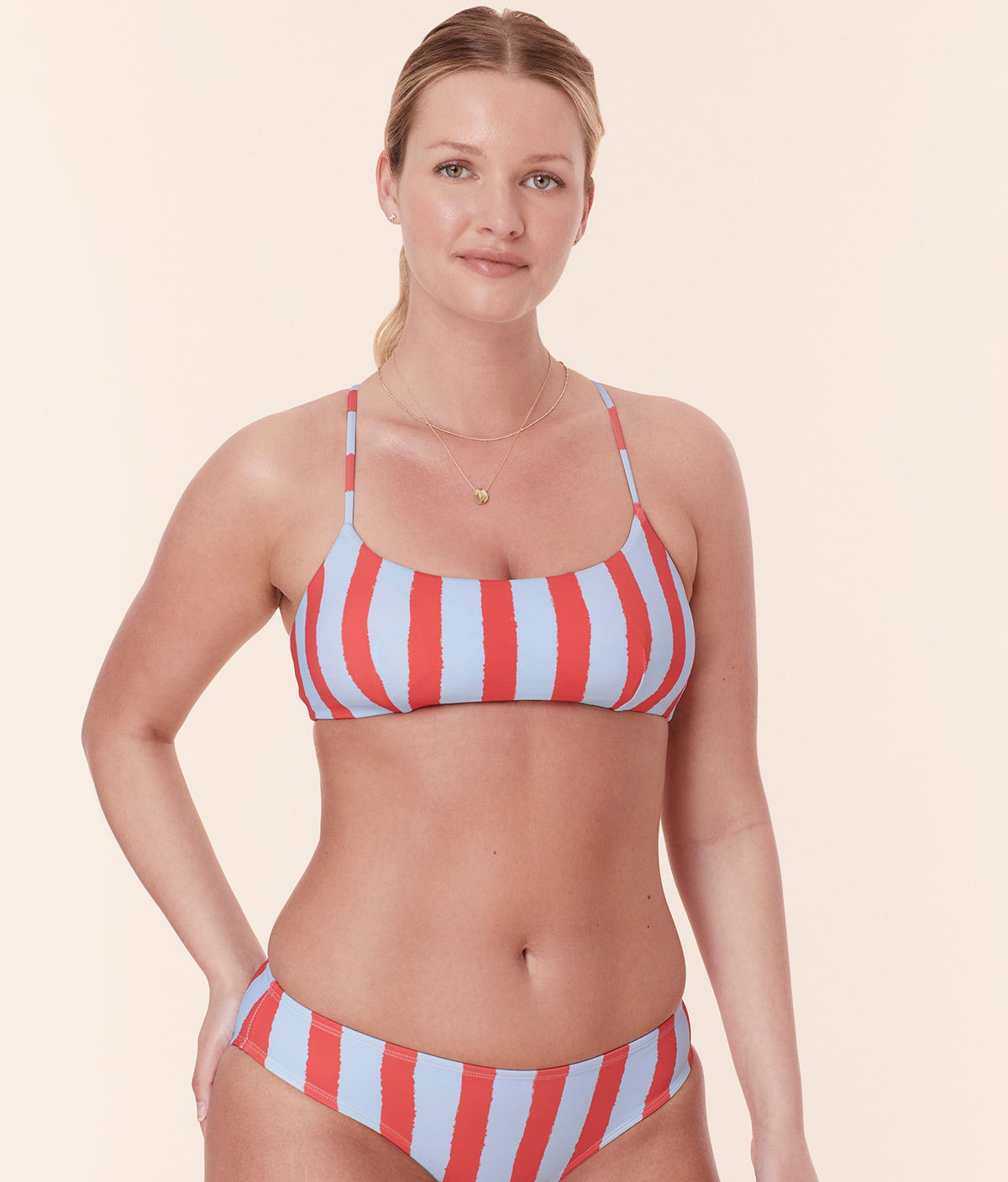 Model wearing Andie Swim's Fiji Bikini Top in Candy Stripe, designed with a scoop neckline and eco-friendly compressive fabric for a comfortable, sculpting fit.