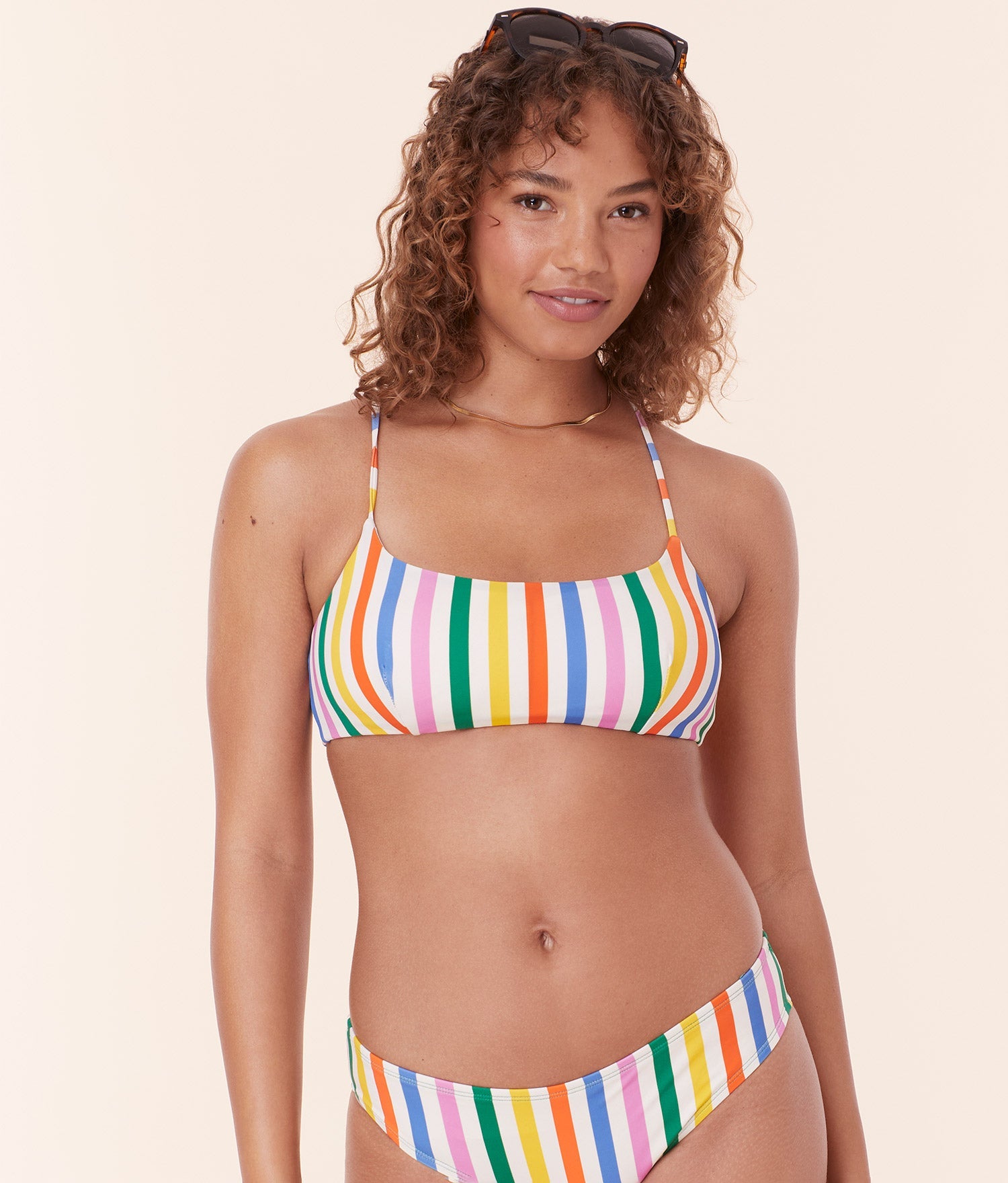 Model in Andie Swim's Fiji Bikini Top in Rainbow Stripe, showcasing the scoop neckline and supportive, eco-friendly design.