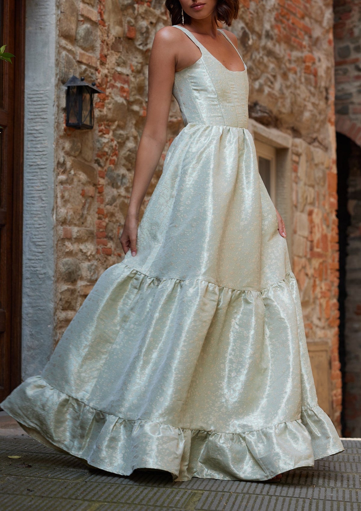 Front view of The Avery Dress in Sage Duchess showcasing its corseted scoop neck and gathered tiers on a model outdoors