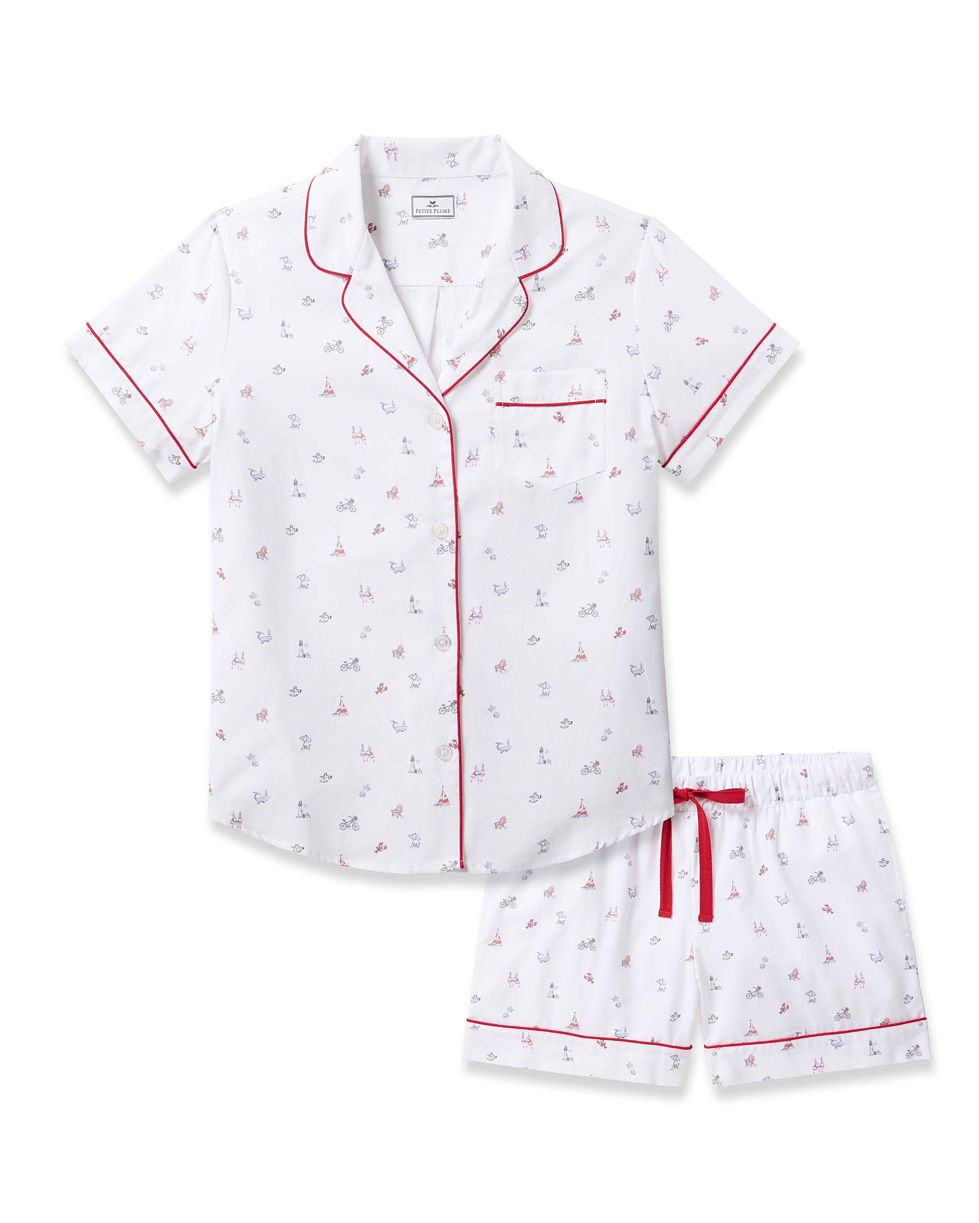 Petite Plumes Womens Twill Short Sleeve Short Set in Coastal Charms features a white cotton pajama set with a red and navy sailboat pattern, collar, chest pocket, red piping, button-up shirt, and comfy shorts with an elastic waistband and red drawstring—luxurious coastal sleepwear.