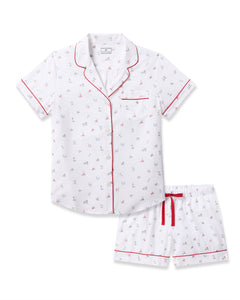 Petite Plumes Womens Twill Short Sleeve Short Set in Coastal Charms features a white cotton pajama set with a red and navy sailboat pattern, collar, chest pocket, red piping, button-up shirt, and comfy shorts with an elastic waistband and red drawstring—luxurious coastal sleepwear.