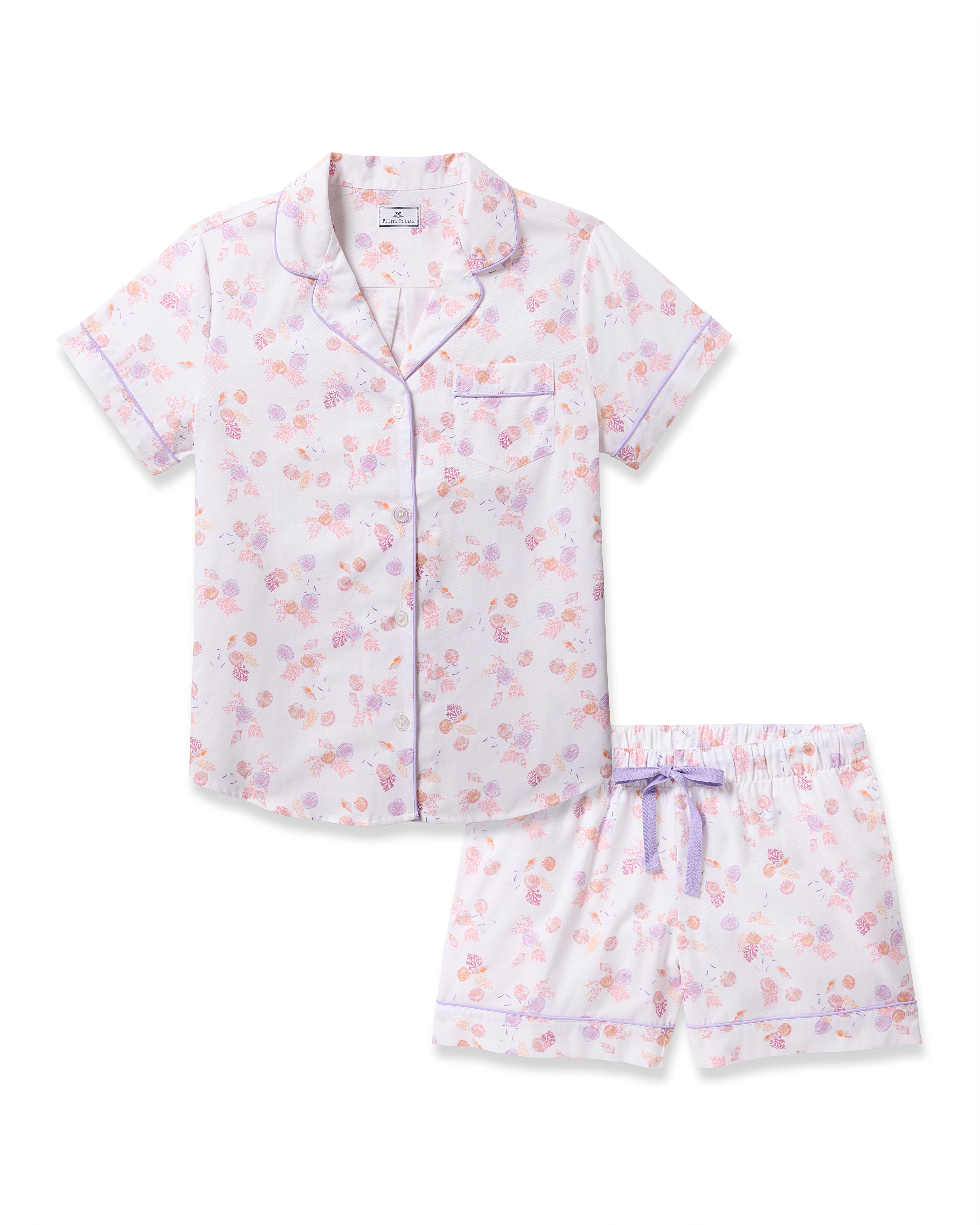 Indulge in luxurious sleep with Petite Plumes Womens Twill Short Sleeve Short Set in Seashell Splendor, showcasing pastel florals on high-quality cotton. The button-up top has a small pocket and purple piping, while the shorts feature an elastic waistband with a purple bow.