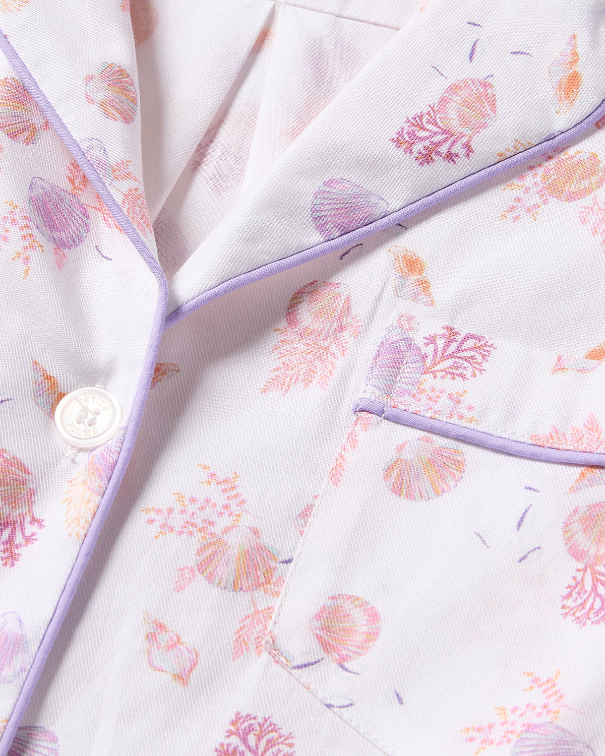 The Petite Plume Womens Twill Short Sleeve Short Set in Seashell Splendor features luxurious cotton fabric with pastel seashell patterns, a chest pocket, buttons, and lilac piping for a delicate and elegant look.