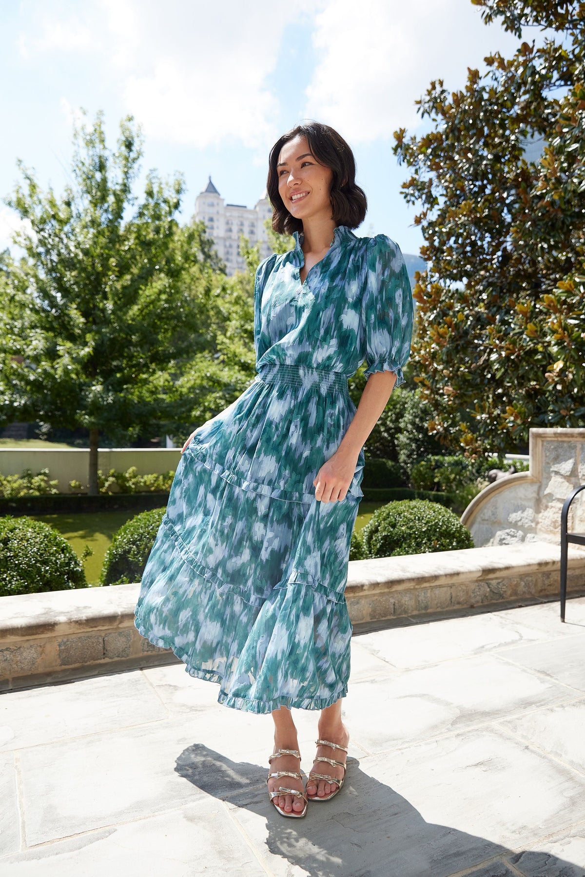 Full-length view of Bennett Gown Teal Ikat Chiffon on model, showcasing smocked waist and tiered ruffle skirt outdoors