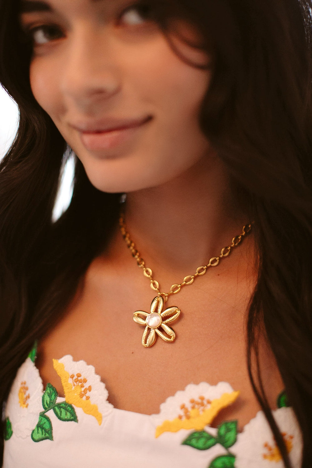 Close-up of Aloha Necklace on model showcasing gold-plated cowrie shell flower pendant with mother-of-pearl center on chain