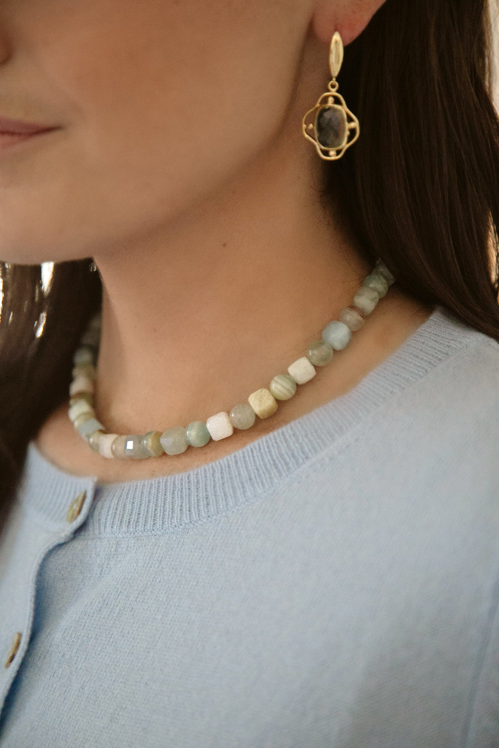 Close-up of Amal Necklace showcasing round calcite and faceted cube amazonite beads on a model wearing a light blue top