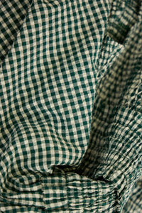 The Eubanks Top has a fitted bodice, puff sleeves, smocked cuffs, shirred yoke, and purl edge trim.
