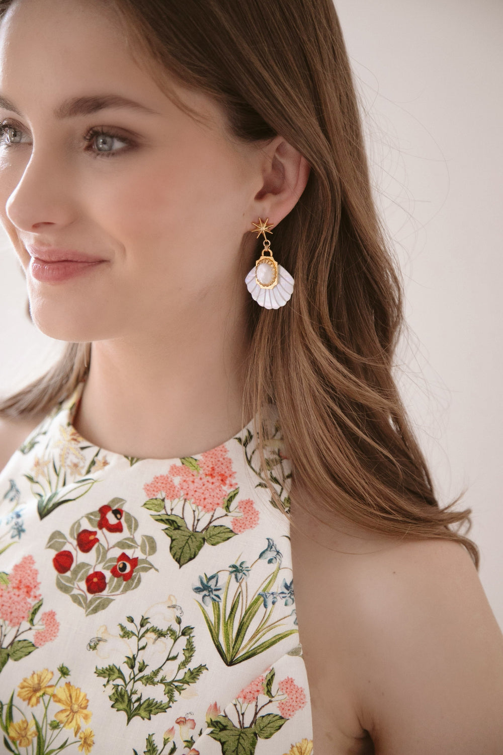 Left profile of Aperitivo Earrings on model showcasing mother-of-pearl fan drops, oval moonstone cabochons, and gold-plated star toppers