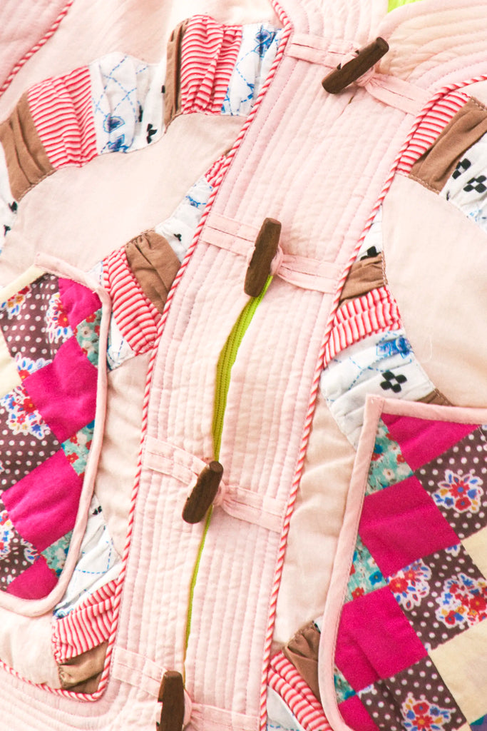 A cropped long-sleeve quilted jacket with a wooden toggle closure in multiple pastels.