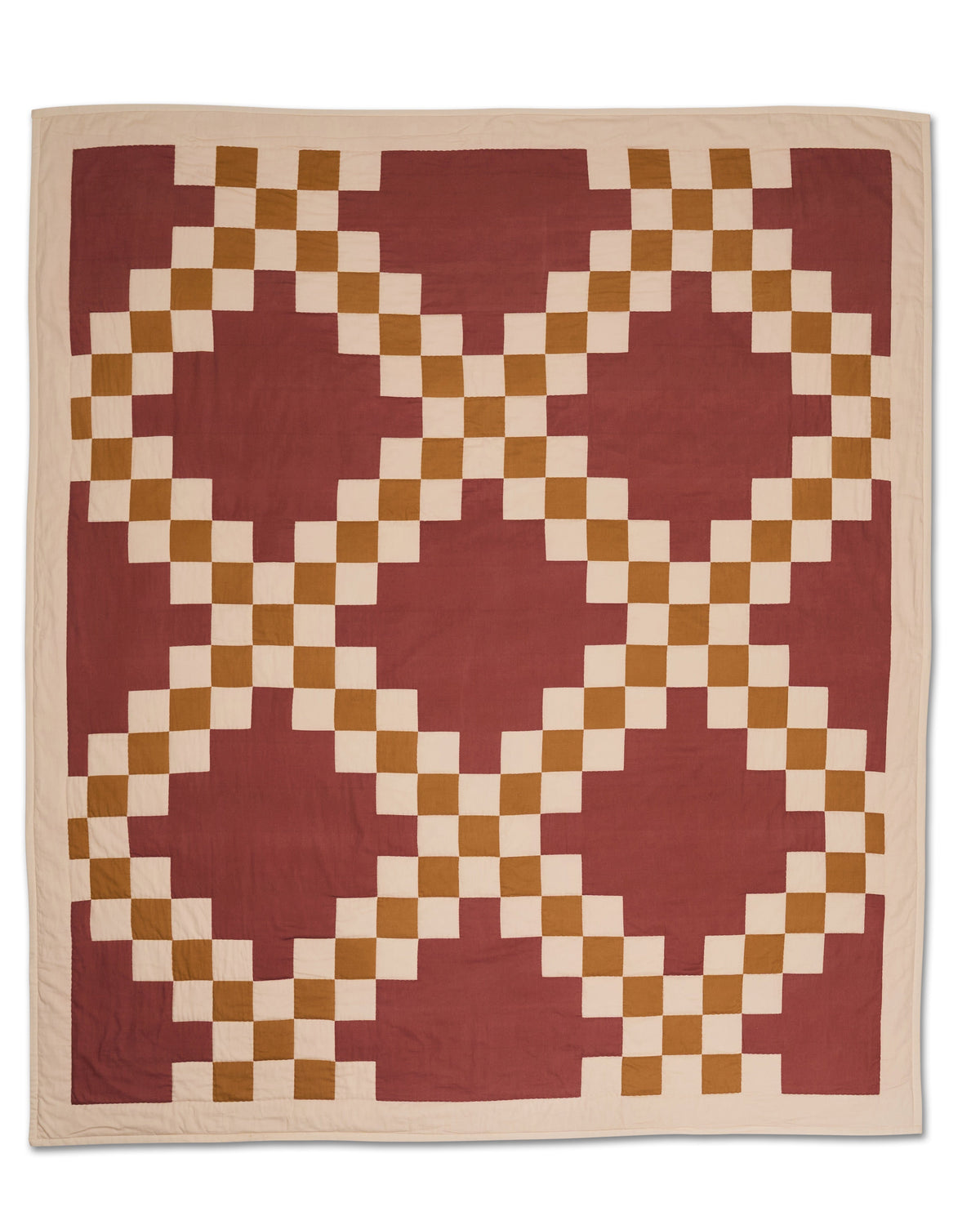 Flat lay of Prairie Quilt showcasing hand stitched checkerboard rings in rust, tan, and cream on a white background