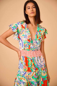 The Aurora Dress has a low-cut wrap ruffle neckline, rope ties, skirt ruffles, and a smocked waist.