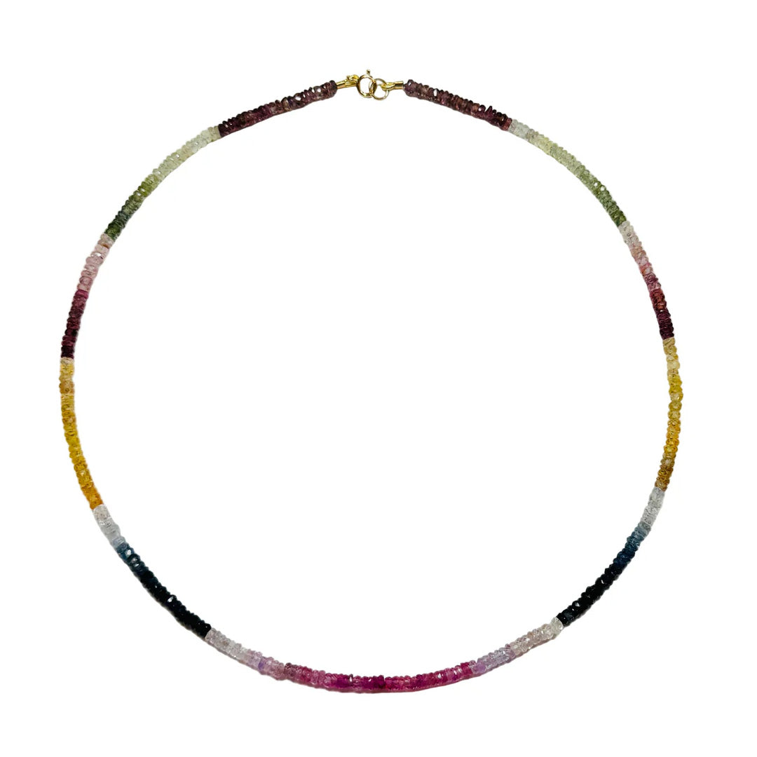 Flat lay of heishi sapphire necklace showing graduated autumn-hued sapphire beads and gold spring-ring clasp on white background