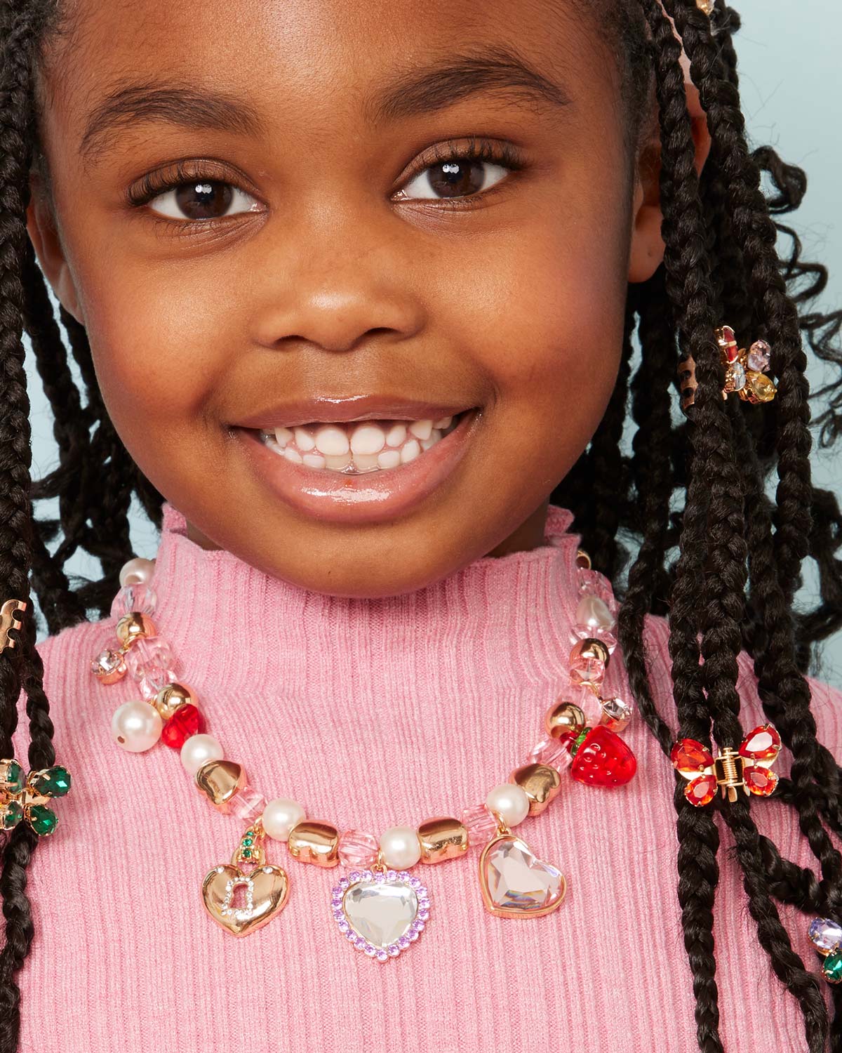 Close-up of Make It Heartfelt Mini Bead Kit showcasing heart charms and assorted beads on a child in a pink sweater